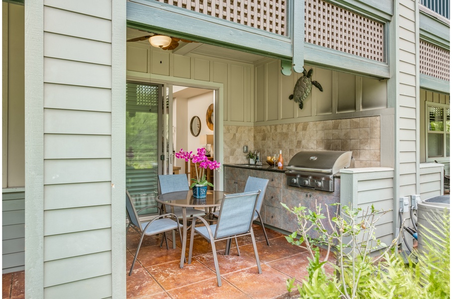 Outdoor gas grill, sink and alfresco dining overlook the beautifully manicured tropical landscape.