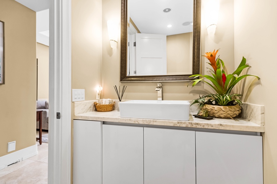 Guest bathroom with clean white cabinetry and floral accents.
