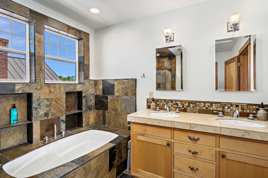 Common bathroom with a hot tub and dual sink