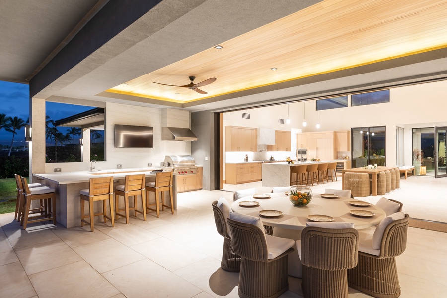 Experience luxury living in this open-concept space where your indoor kitchen flows seamlessly to outdoor dining under elegant ceiling lighting.