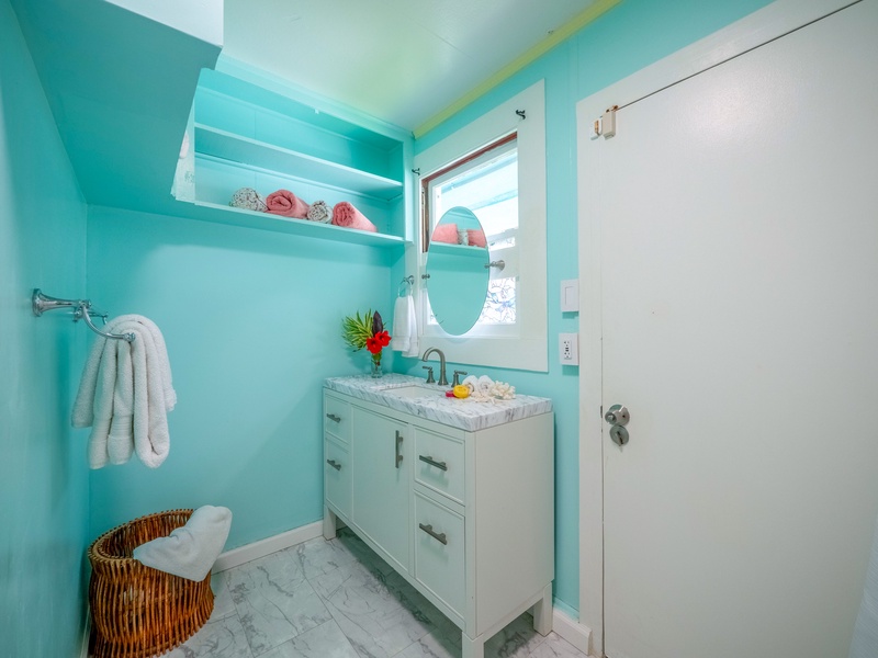 Refresh in your bright turquoise bathroom with marble counters, fluffy towels, and cheerful coastal charm.