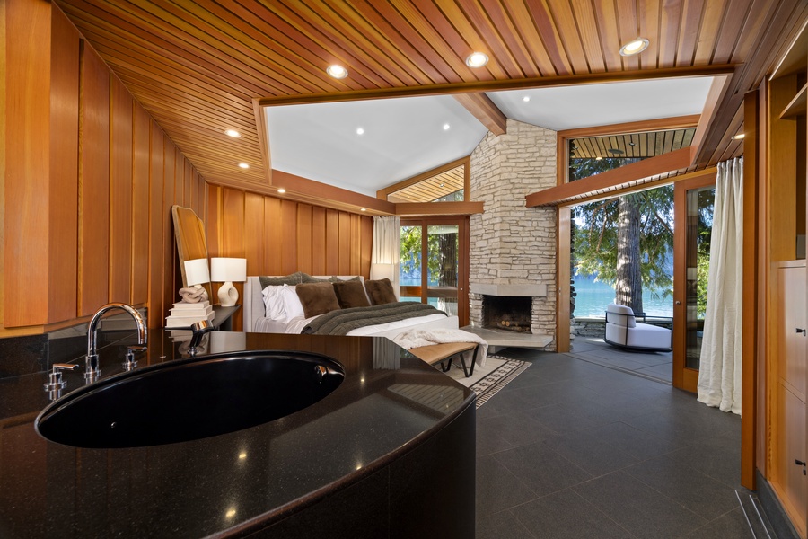 Your luxury suite features a dramatic soaking tub, cozy fireplace, and stunning lake views through floor-to-ceiling windows.