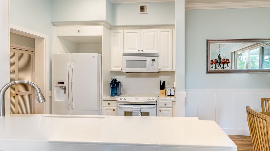 The bright kitchen features many amenities including a fridge, oven, extended counter-tops and high ceilings.