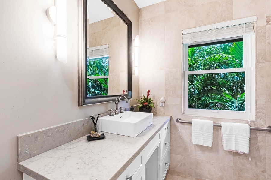Elegant en-suite vanity with tropical views and granite countertop.