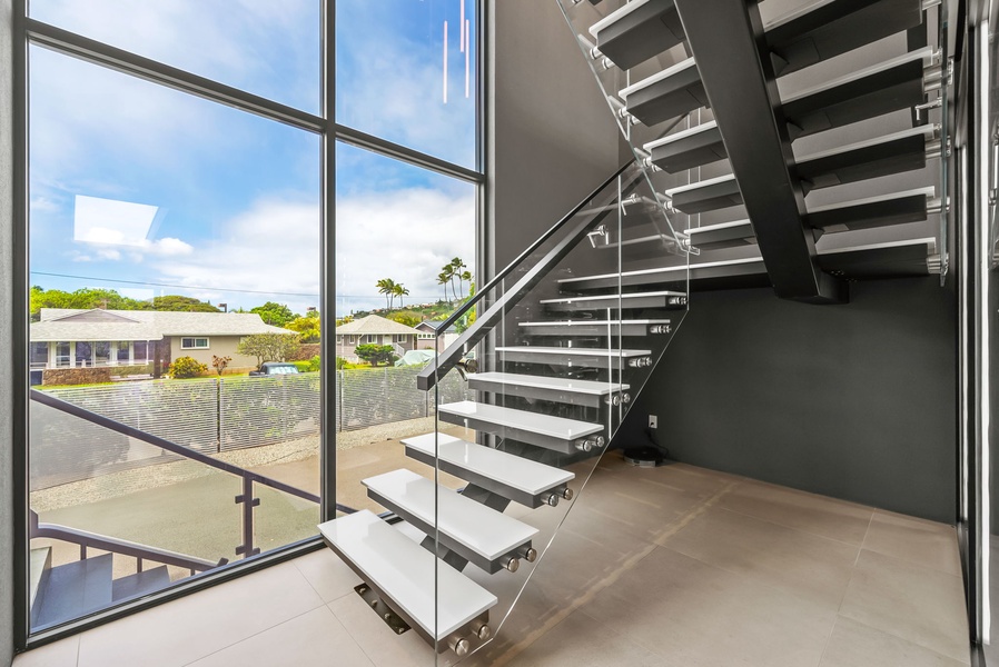 Floating staircase framed by floor-to-ceiling windows and natural light.