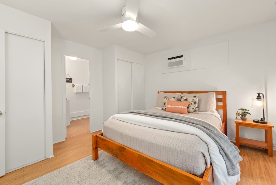 Drift off in this serene bedroom with your cozy bed, sleek air conditioning, and gentle ceiling fan overhead—your perfect retreat after a day of exploring.