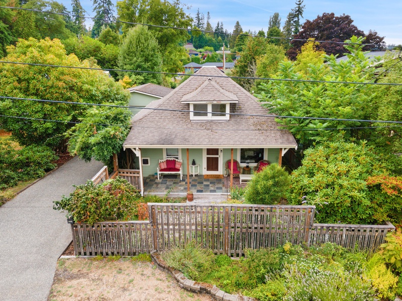 Arrive at this charming cottage-style home surrounded by vibrant landscaping, inviting you into its warm and cozy ambiance.