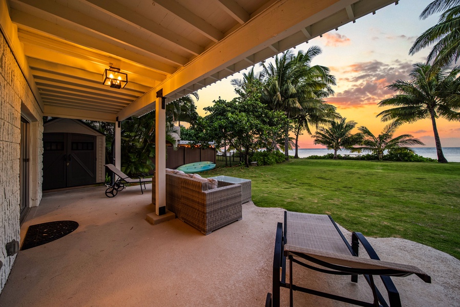 Outdoor seating under a lit lanai, steps from the beach.