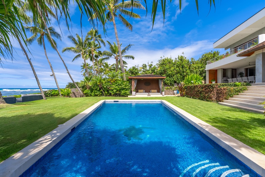 Modern beachfront estate featuring a pristine pool, swaying palms, and oceanfront location. The property includes landscaped grounds, covered lounge area, and coastal access—an idyllic tropical retreat.