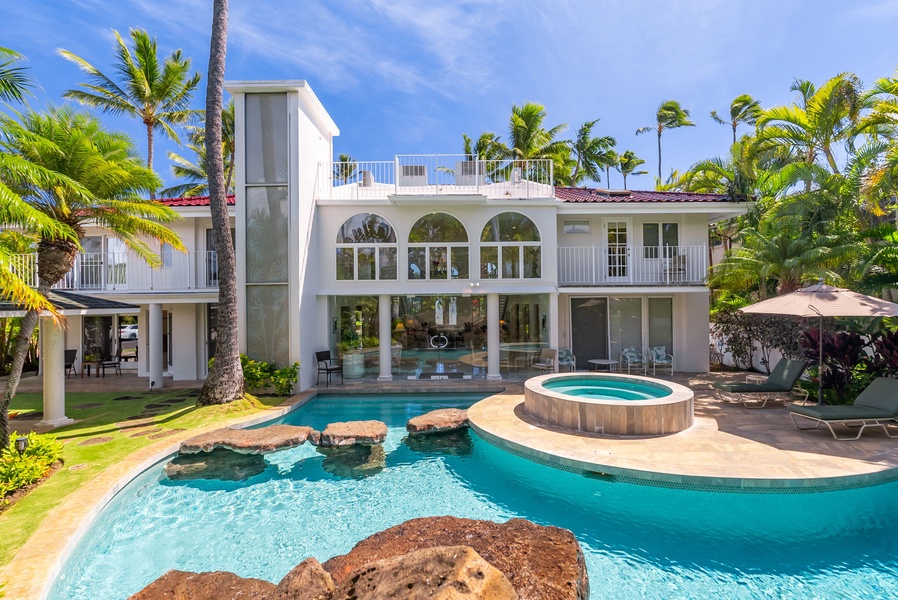 View of the villa’s backyard featuring a large pool, spa, and tropical landscaping, creating a resort-like atmosphere.