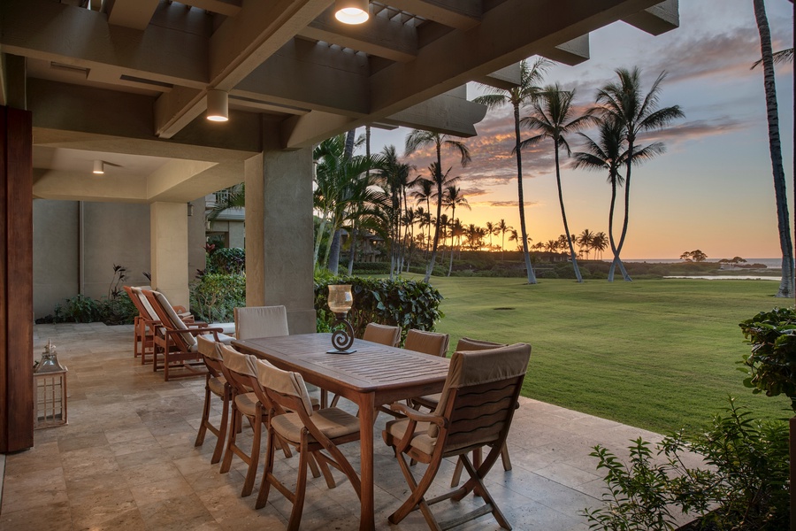 Wide view of lanai seating at sunset, with dining table and loungers beyond.