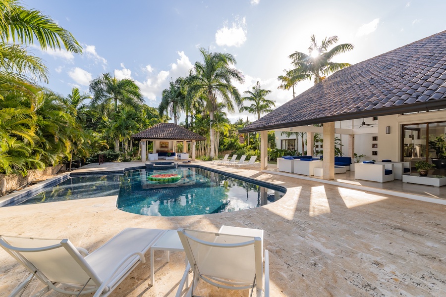 Expansive poolside area with ample seating and lush palm trees, creating a tranquil tropical escape at Casa de Campo.
