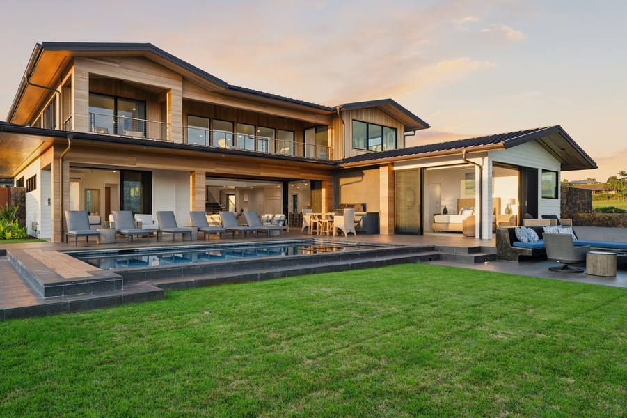 Modern luxury home featuring a pristine swimming pool and expansive outdoor entertaining areas set against a beautiful sunset sky.