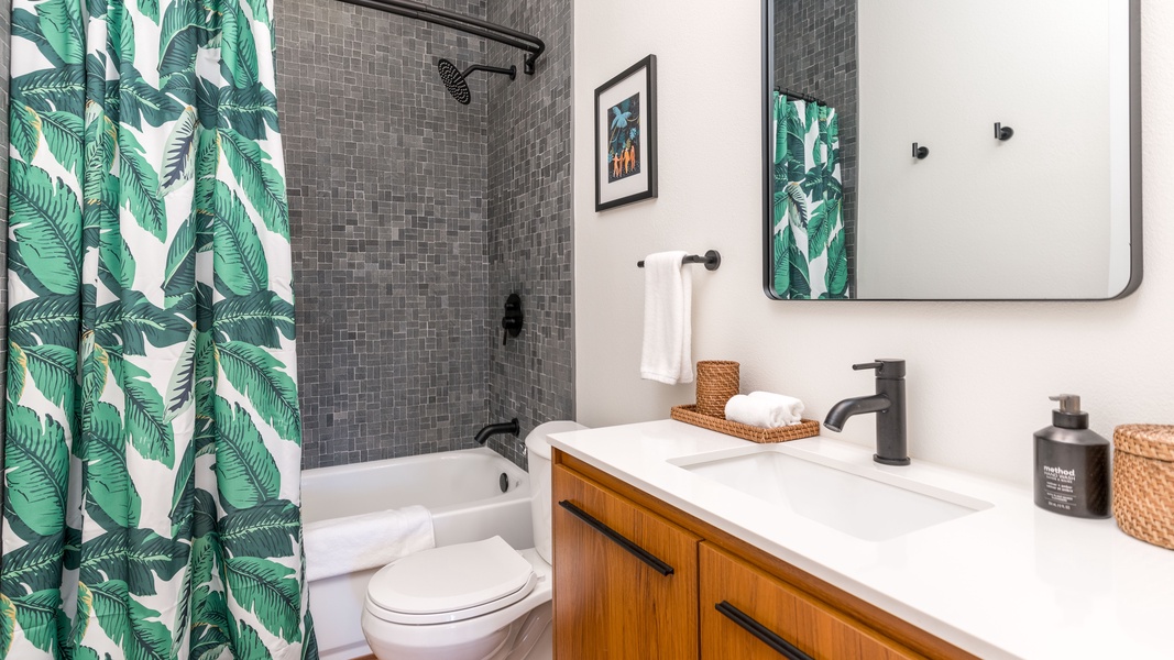 The downstairs guest bathroom with a shower and tub combo and striking design.