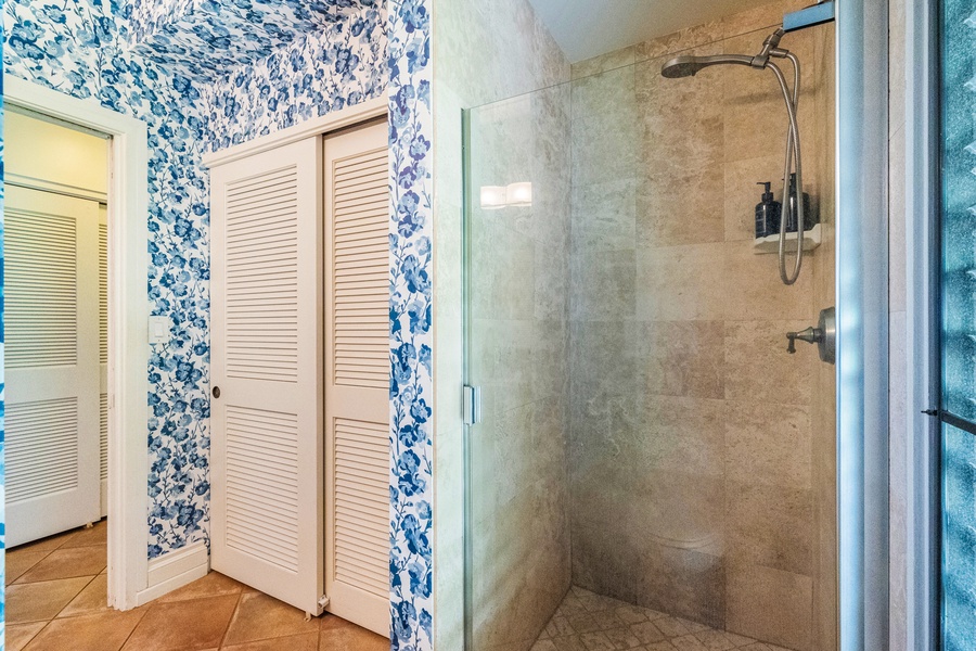 A cozy hallway leads to a bedroom featuring vibrant blue accents and patterned wallpaper for a fresh, coastal feel.