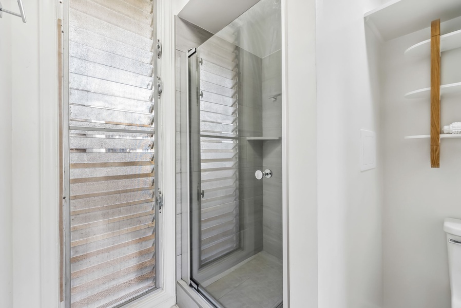 Modern walk-in shower with glass doors and stylish tilework.