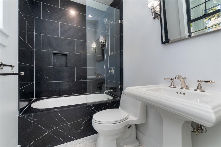 Bold contrast guest bath featuring dark tile and pedestal sink.