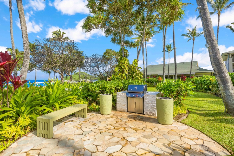 Outdoor barbecue area surrounded by tropical palms and lush gardens, with ocean views in the background.