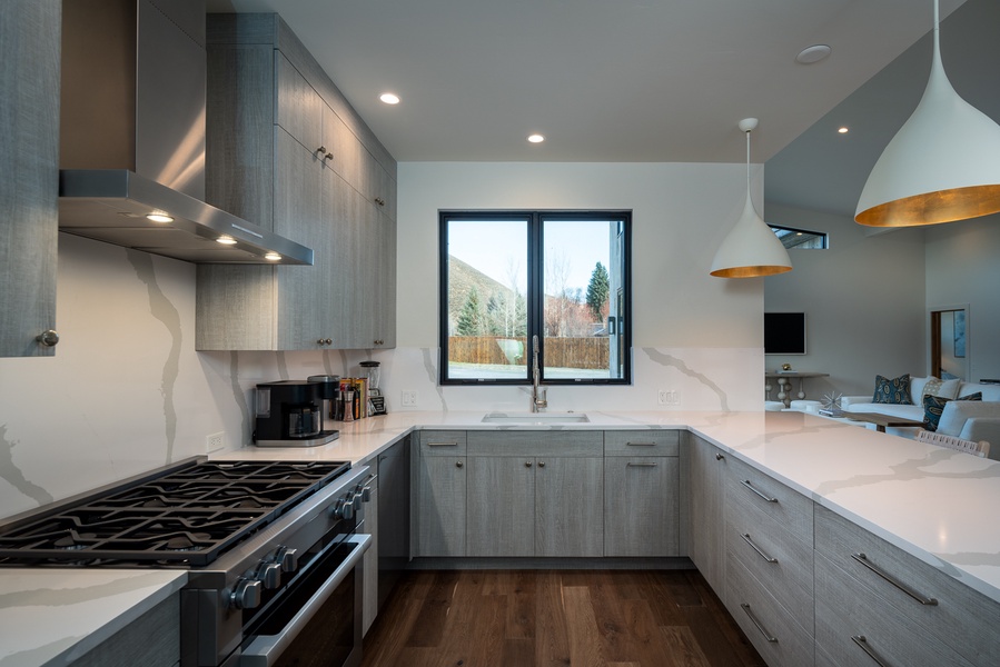Sleek fully-stocked kitchen design with top-of-the-line appliances, nestled in natural wood finishes and serene views—culinary creativity awaits.