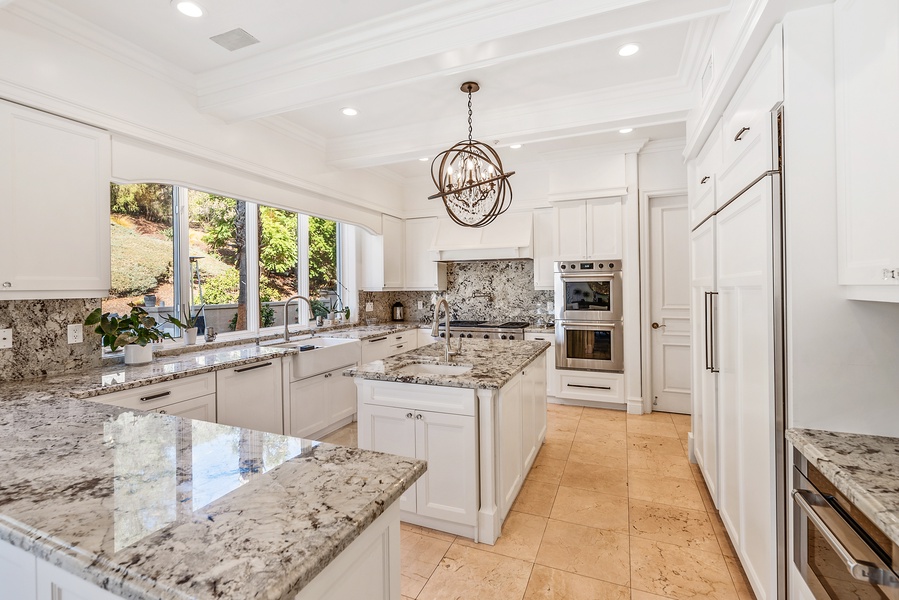 The kitchen area with lots of light, the kitchen is open to an informal dining area, breakfast bar with seating, and French doors to the outdoor kitchen and pool area.