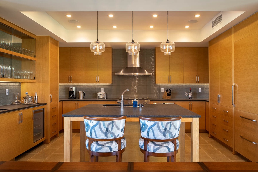 Chefs Kitchen with wolf oven and gas cooktop, Sub-Zero refrigerator, Sub-Zero under-counter wine cooler, and a bar with sink and Sub-Zero ice maker.