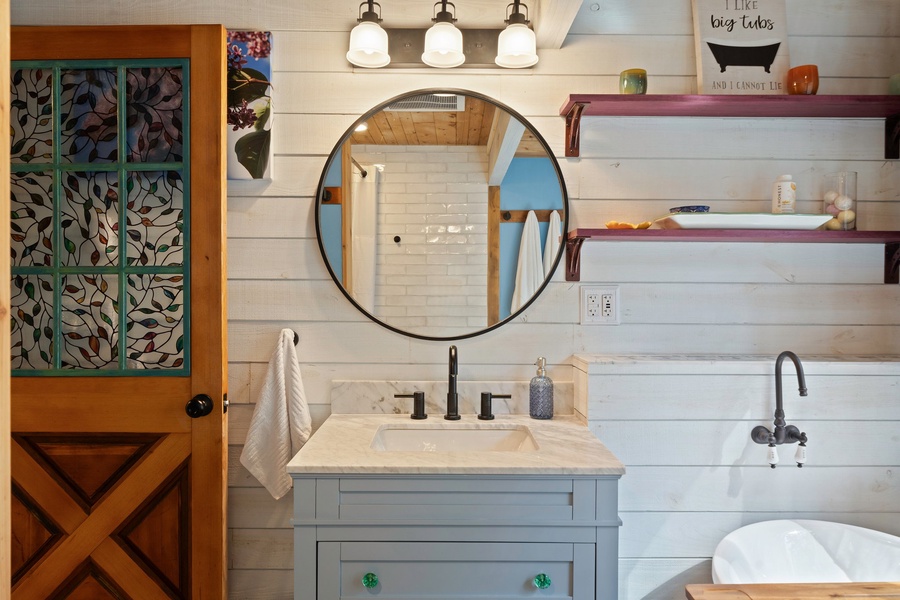 A stylish vanity and round mirror elevate the bathroom's design while keeping your daily routine comfortable and easy.