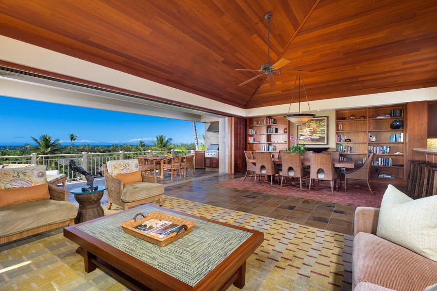 Ample living area plush lounge seating, receding pocket doors to lanai, and formal interior dining area.