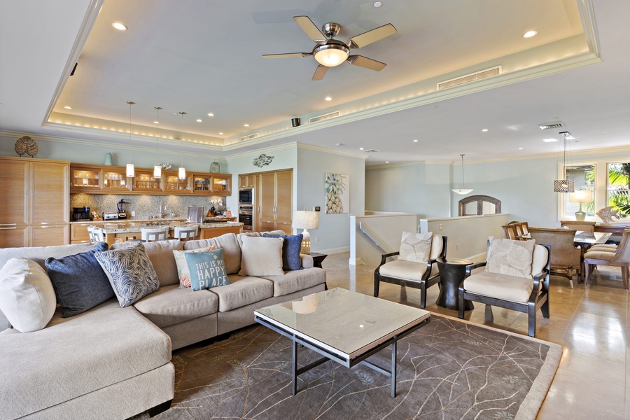 Wailea Hoolei 93-3 offers a spacious living area with a plush sectional, modern fan, and seamless flow into the kitchen.