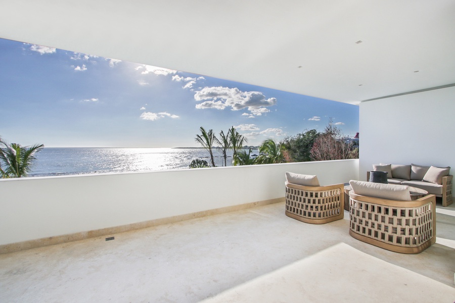 Lounge on the balcony with cozy seating and stunning ocean views.