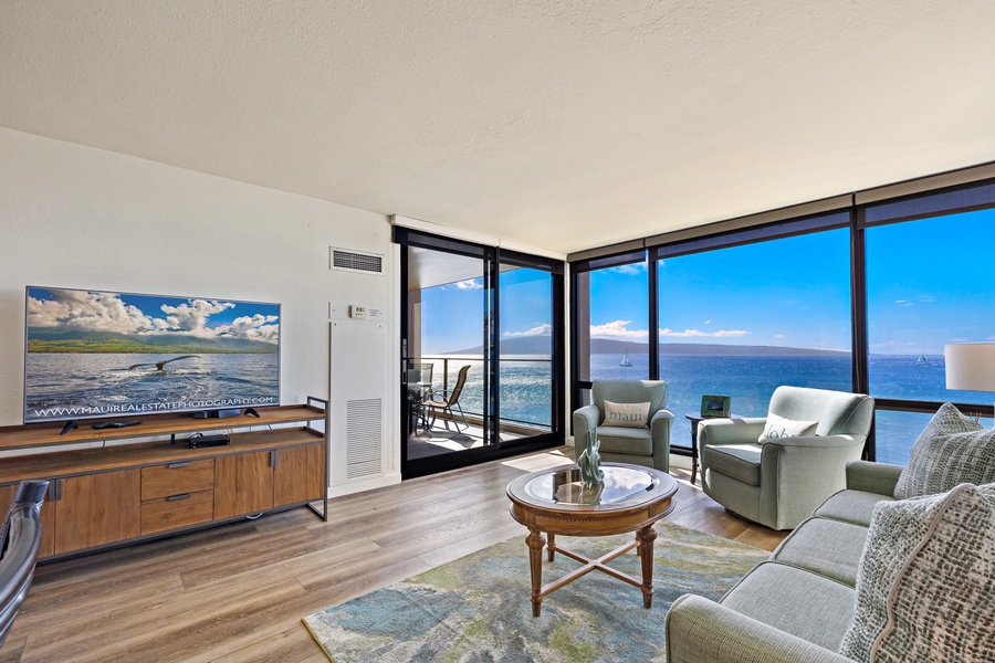 The living room features expansive ocean views, complemented by comfortable seating and a sleek entertainment center, perfect for unwinding after a day of island adventures.