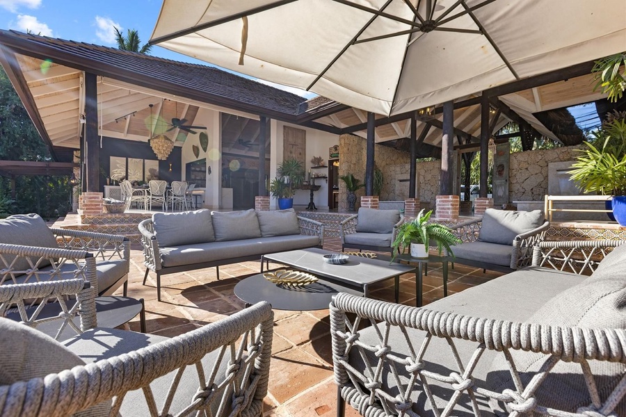 A cozy outdoor seating area with plush sofas and an oversized umbrella, perfect for relaxing under the shade.