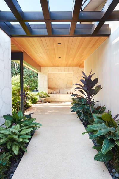 A beautifully designed covered walkway welcomes you home, blending warm natural materials, tropical landscaping, and contemporary island architecture.