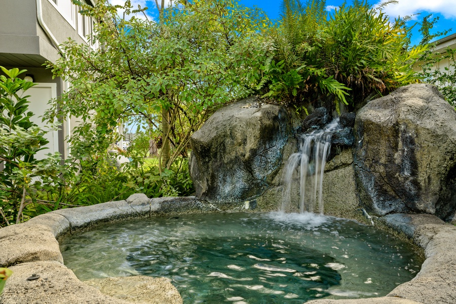 Tranquil outdoor pool surrounded by natural stone and vibrant landscaping, offering a serene escape.