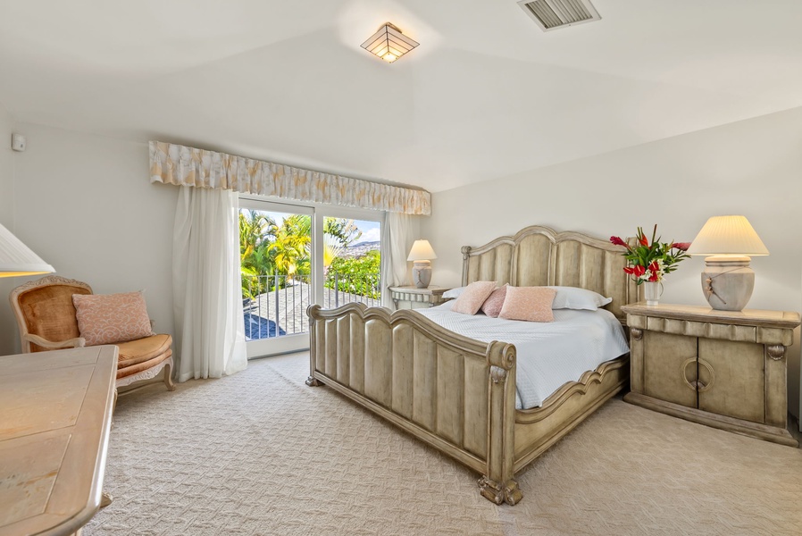 Charming fourth guest suite with a classic king-sized bed and French doors leading to a private balcony with tropical views.