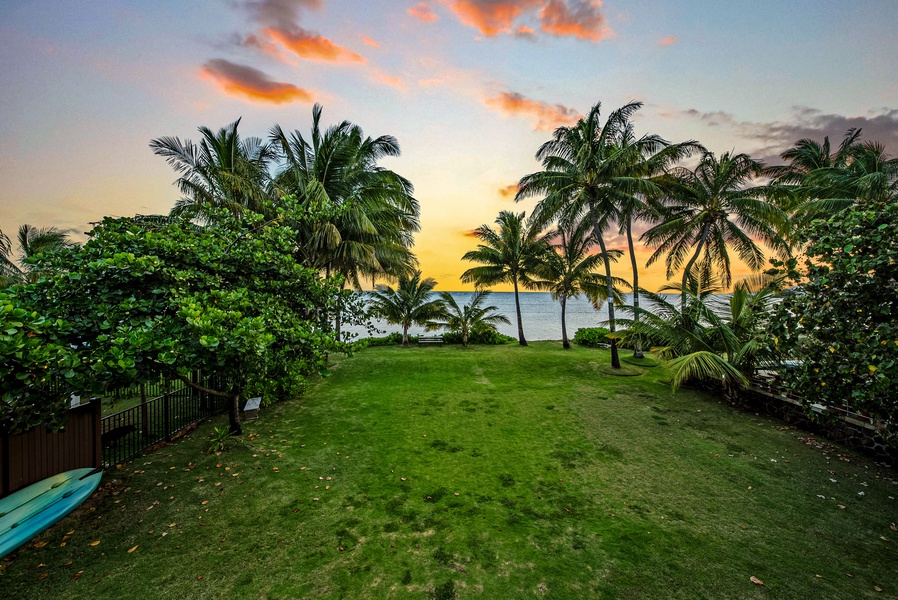 Backyard framed by lush palms and glowing sunset skies.