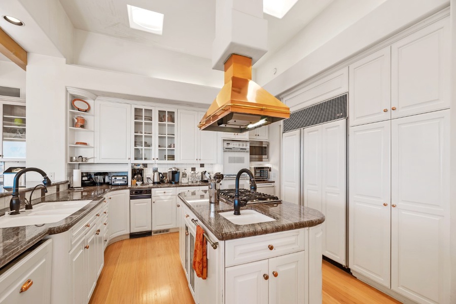 The gourmet Kitchen has high-end appliances, granite counters and unique copper hood