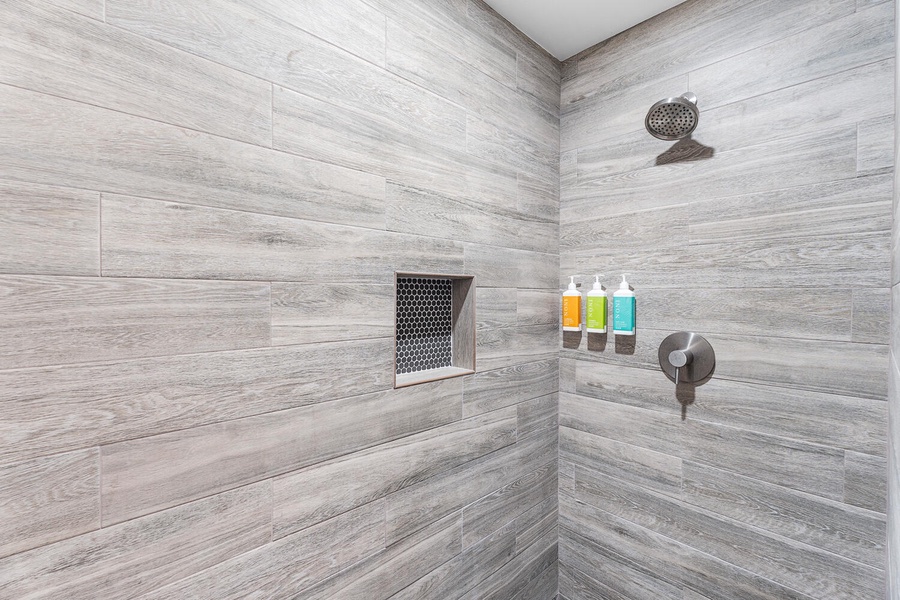 Stylish walk-in shower with rainfall head and modern tile—refreshing after a beach day.