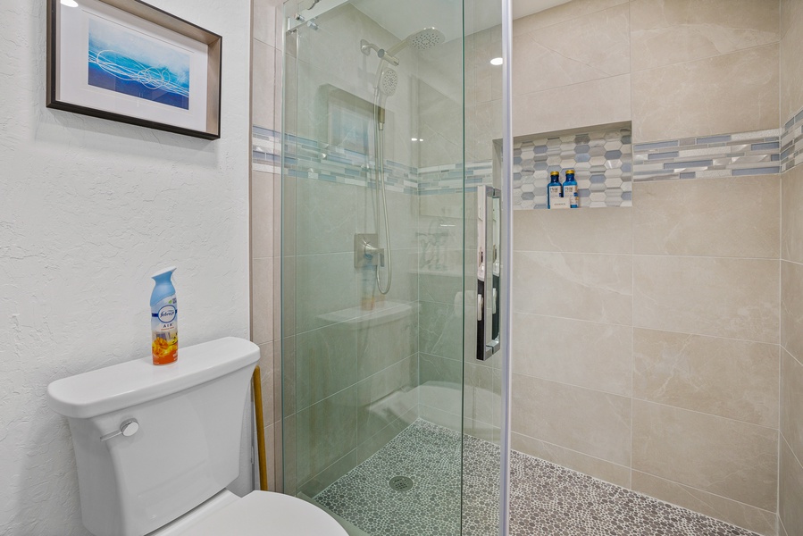 A modern and welcoming bathroom with a sleek glass-enclosed shower, elegant tiles