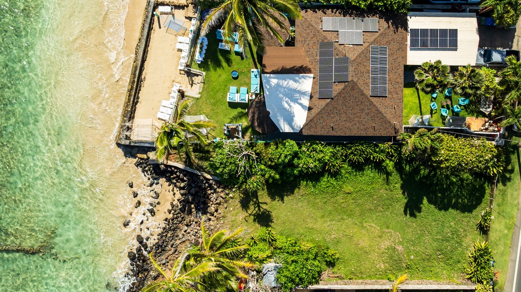 Stunning aerial view of a beachfront property with tropical gardens and private outdoor spaces.