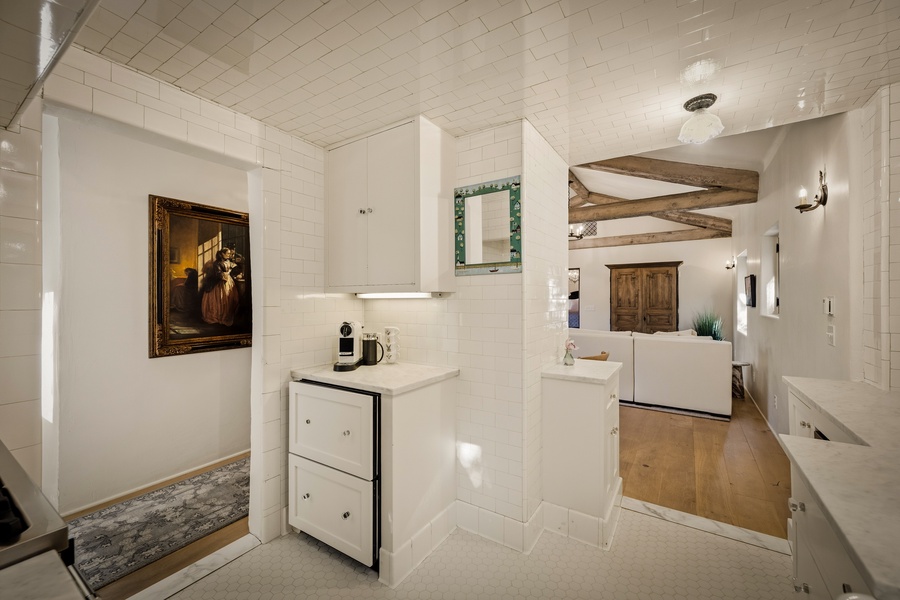 Step into your charming white kitchen where rustic beams meet modern convenience, creating the perfect space for morning coffee.