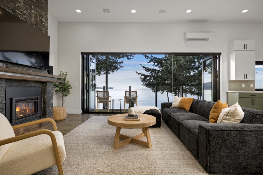 Seamless indoor-outdoor living with glass doors leading to the furnished patio and breathtaking waterfront backdrop.