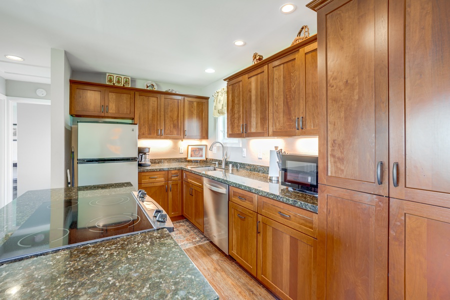 Featuring rich wooden cabinetry, sleek appliances, and a convenient island, it is perfectly equipped for crafting meals with the fresh flavors of the islands.