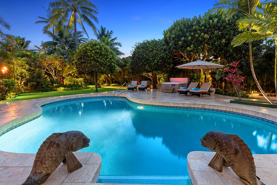 Bright blue pool surrounded by palm trees and tropical gardens, offering a serene escape.