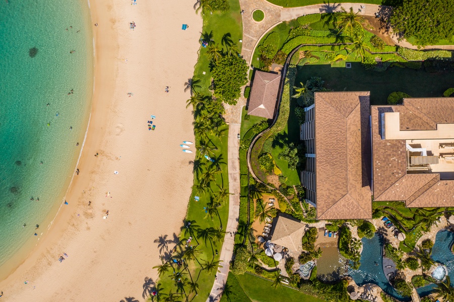 Overhead, a villa sits between the beach and its own green grounds.
