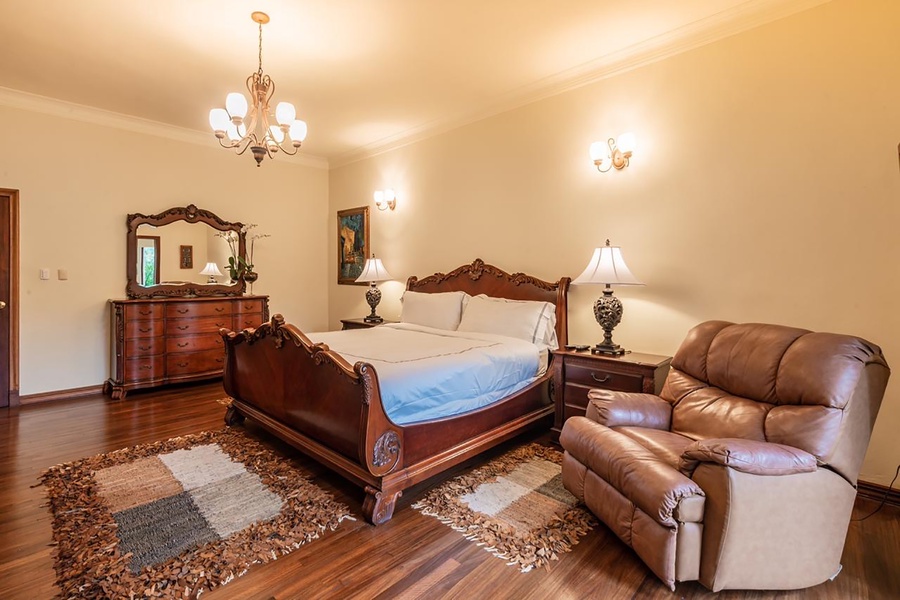 The elegant third guest bedroom also features a cozy recliner, classic dresser and decor.