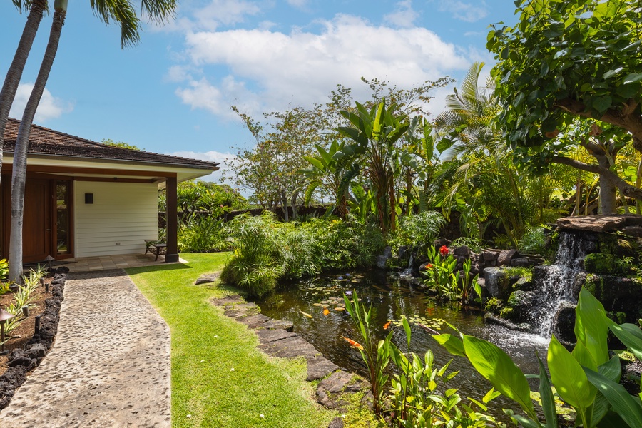 Tropical footpath alongside koi pond and gardens—tranquil island ambiance begins at the entrance.