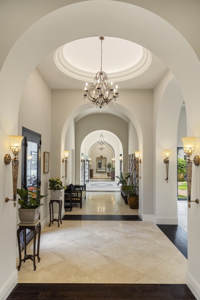 Grand hallway with arched ceilings, chandeliers, and a timeless design leading to the main living areas.