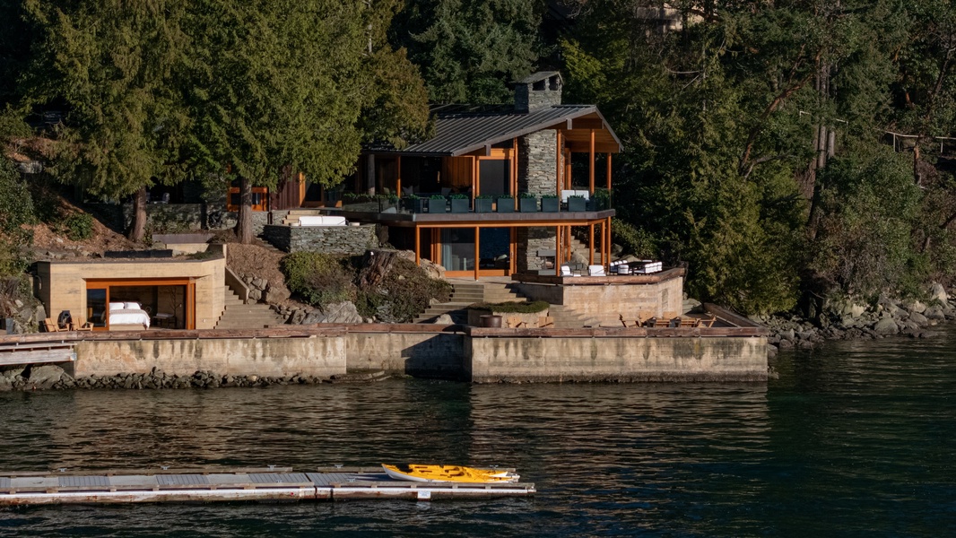 Stunning waterfront property with modern architecture nestled among towering trees, featuring private dock access and serene lake views.