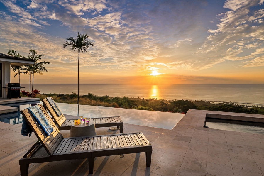 Spectacular oceanfront terrace showcasing a breathtaking sunset over the Pacific, featuring infinity pool and tropical landscaping with palm trees.