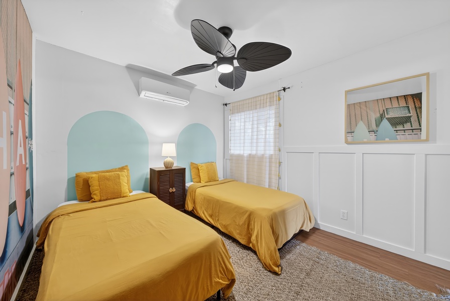 Cozy twin bedroom with surf-inspired wall art, creating a fun and relaxing beachside retreat.